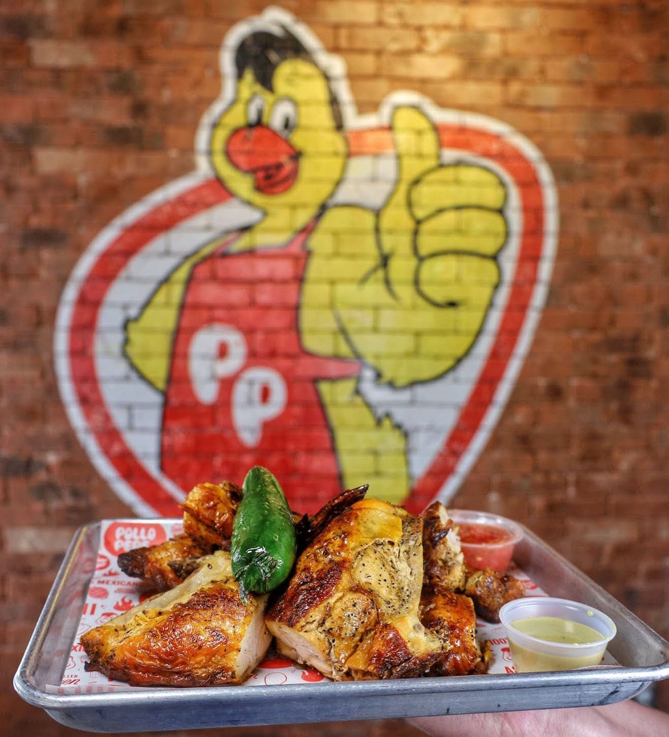 A tray of pollo asado held up in the restaurant